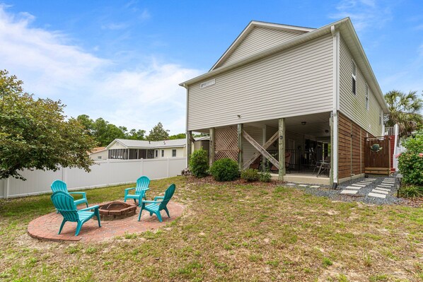A two-story house with a covered porch and a brick fire pit area.