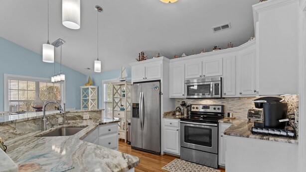 A modern kitchen with white cabinets, stainless steel appliances, and a marble countertop. - Discover Peaceful Palms, a charming 3-bedroom home in Oak Island's East Beach (Oak Island)