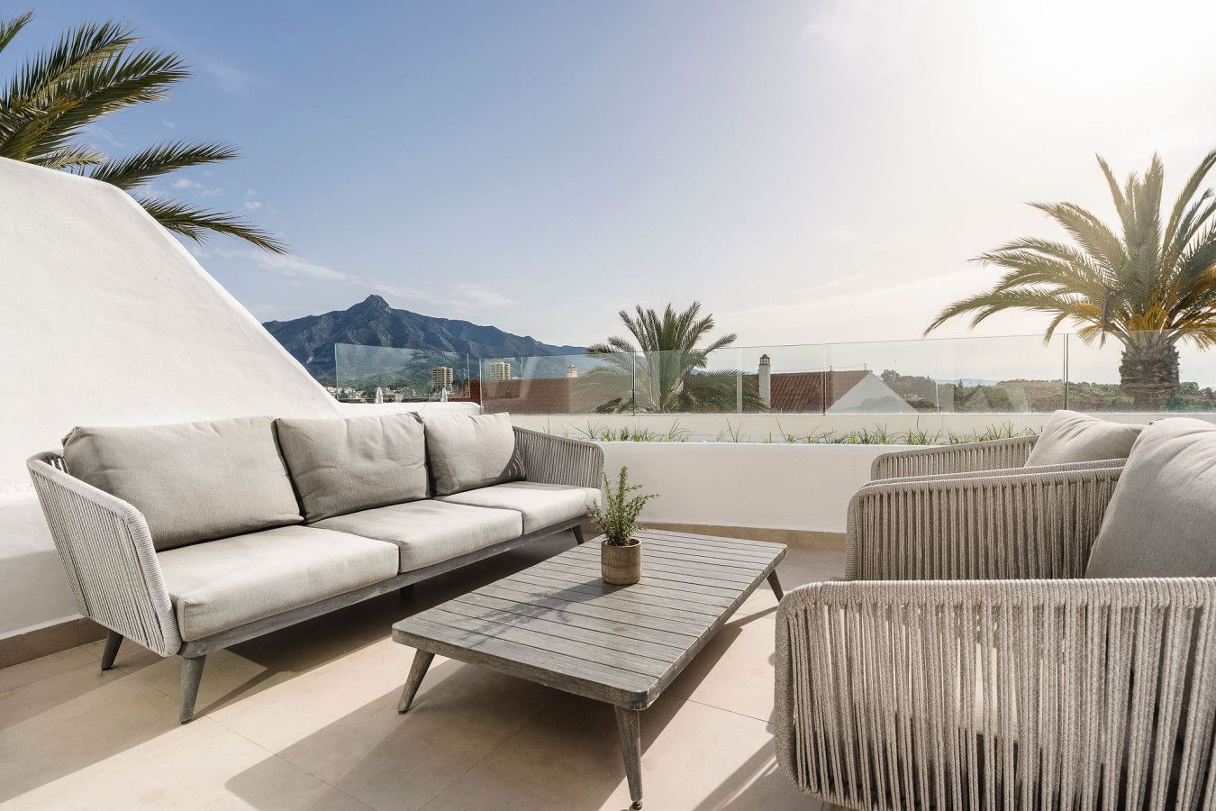 Eine Dachterrasse mit einer Couch, Stühlen und einem Tisch.