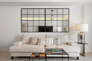A modern living room with a sofa, a coffee table, and a lamp.