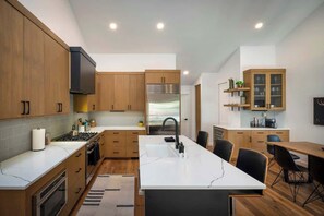 A modern kitchen with wooden cabinets, a central island, a built-in oven, and a stainless steel refrigerator. - Abode at Sunnyside, modern mountain chic, Ketchum (Ketchum)