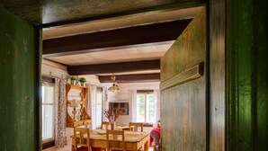 A wooden dining room with a table and chairs, a hanging light fixture, and a view of the adjacent room. - Vacation home Marta by Interhome (Smržovka)