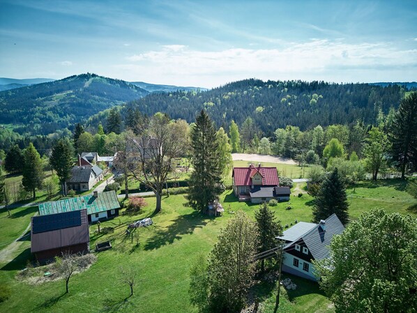 A rural landscape with houses, green fields, and forested hills.