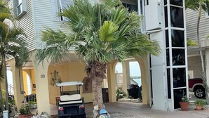A building with a covered entrance, a golf cart, and a palm tree. - Tides & Tranquility - Venture Out Unit 053 (Summerland Key)