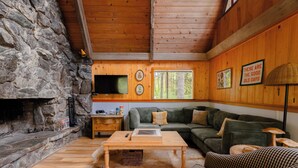 Una sala de estar acogedora con chimenea de piedra, techo de madera y un sofá verde.