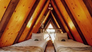 Un dormitorio acogedor en el ático con dos camas, vigas de madera y vistas al exterior.