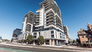 A multi-story building with balconies, a modern architectural design, and a clear sky.