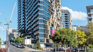 A modern high-rise building with a curved facade, large windows, and a mix of balconies and terraces.