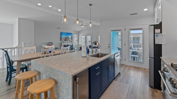 A modern kitchen with a large island, stainless steel appliances, and a view to the outside.