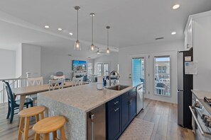 A modern kitchen with a large island, stainless steel appliances, and a view to the outside.