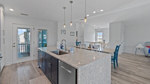 A modern kitchen with a large island, stainless steel appliances, and pendant lighting.