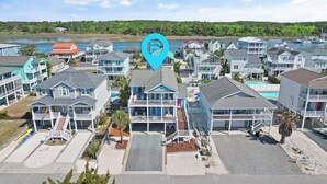A coastal residential area with multiple two-story houses, a central building with a balcony, and a body of water in the background.