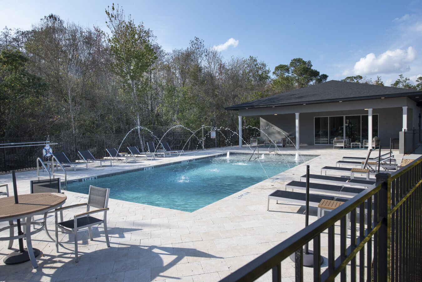 A swimming pool with lounge chairs and a covered seating area.