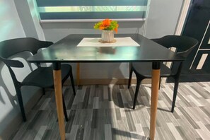 Une pièce moderne avec une table en verre, deux chaises noires et un plancher en bois.
