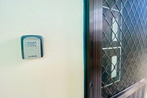 A keypad lock on a wall, a metal mesh window, and a door frame. - Studio at Amplayo Apartelle – Stylish, Budget-Friendly City Stay (Cagayan de Oro)