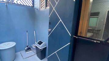 Un baño con una pared azul, un bote de basura blanco, un trapeador y un cubo.