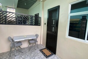 A small outdoor area with a table and chairs, a black gate, and a window. - Studio at Amplayo Apartelle – Stylish, Budget-Friendly City Stay (Cagayan de Oro)