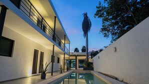 Un edificio moderno con piscina, balcón y una palmera.