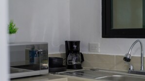Una cocina equipada con microondas, cafetera y lavamanos.