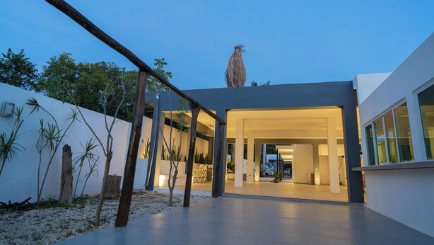 Un edificio moderno con un amplio espacio exterior, una estructura de madera y un pájaro posado en la parte superior.