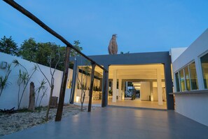 A modern building with a spacious outdoor area, a wooden structure, and a bird perched on top. - PEREGRINA 270 (Motul)