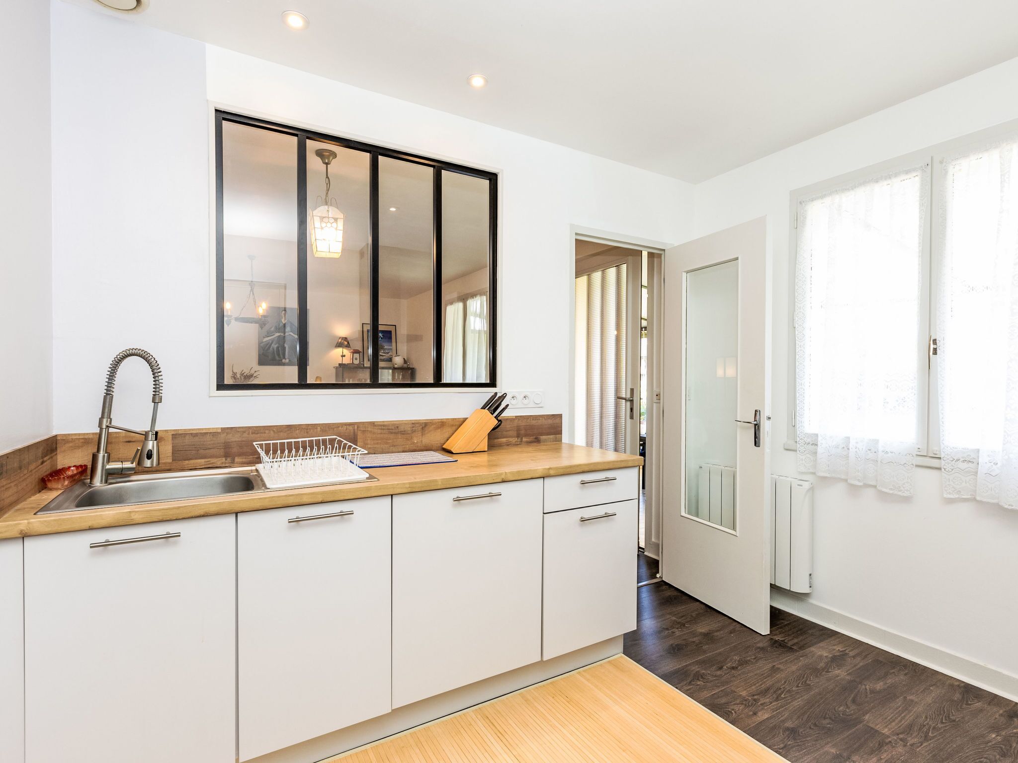 A modern kitchen with white cabinets, a stainless steel sink, and a wooden countertop.
