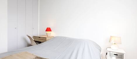 Et soveværelse med seng, natbord, skrivebord og garderobeskab.