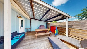 A covered outdoor patio with a wooden table, benches, and a small table. - Pet Friendly, Old Town Location, Golf Cart Access, Close to the Beach (Port Aransas)
