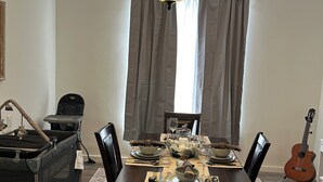 A dining area with a chandelier, dining table set with plates, glasses, and a guitar in the background.