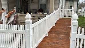 A house with a front porch, white picket fence, and a brick pathway leading to the entrance.