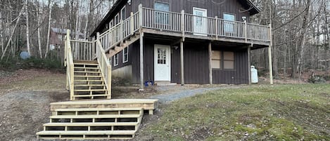 A wooden cabin with a balcony, a staircase, and a door.