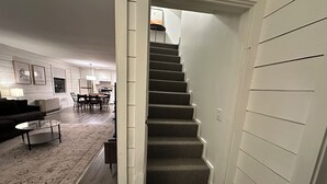 A staircase leading to a second floor, a dining area with a table and chairs, and a living room with a sofa and coffee table.