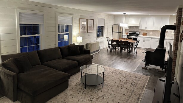 A modern living room with a dark brown sofa, a glass coffee table, and a patterned rug.