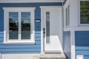Une maison avec une porte d’entrée blanche, un petit porche et une boîte aux lettres.
