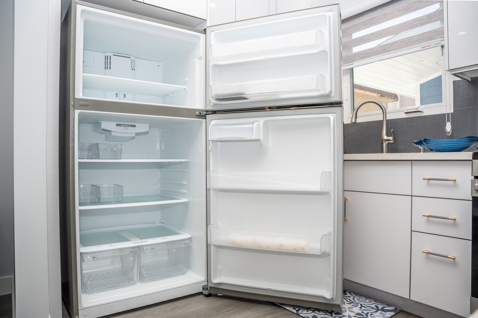 A modern kitchen with a built-in refrigerator, a sink, and a window above the countertop.