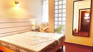 A spacious bedroom with a large bed, a nightstand, a wall-mounted lamp, a window with blinds, and a mirror on the wall. - Torre Verde 2 Pools Tenis Praia da Rocha Beach (Portimão)