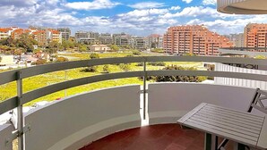 A balcony with a view of a cityscape, a table, and a chair. - Torre Verde 2 Pools Tenis Praia da Rocha Beach (Portimão)