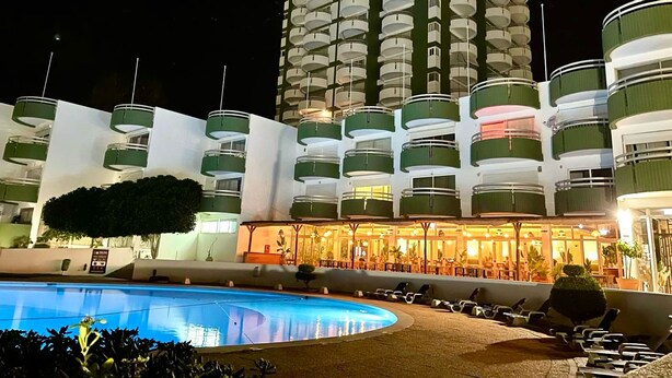 A hotel with multiple balconies, a swimming pool, and a well-lit lobby area. - Torre Verde 2 Pools Tenis Praia da Rocha Beach (Portimão)
