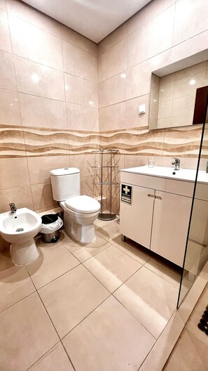 A modern bathroom with a toilet, bidet, and sink, featuring a marble backsplash and a glass shower enclosure. - Torre Verde 2 Pools Tenis Praia da Rocha Beach (Portimão)