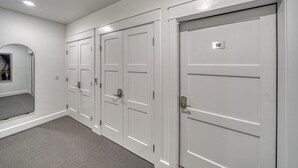 A hallway with white doors, a mirror, and a carpeted floor. - The Mayfly Hotel, Unit 1E (Salida)