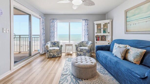 A room with a balcony, a ceiling fan, a sofa, two armchairs, and a small table. - Beautiful Ocean Front Condo - Cherry Grove (North Myrtle Beach)