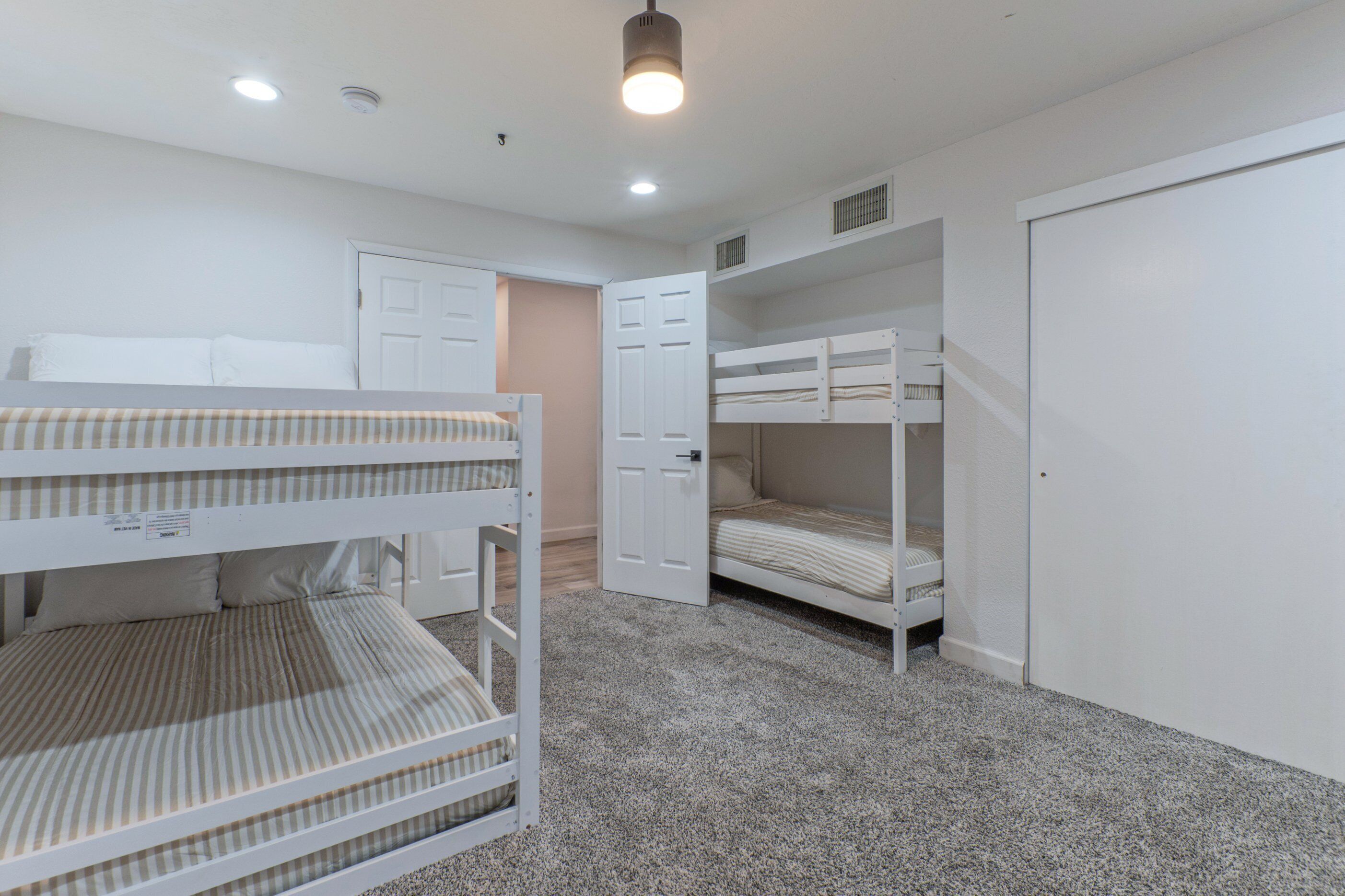 A room with bunk beds, a door, and a ceiling light.