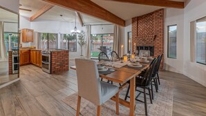 A spacious kitchen with a brick wall, wooden beams, and a dining area with a table set for six.