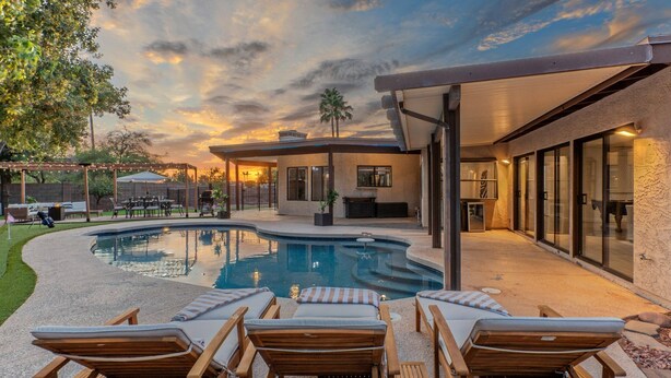 A modern outdoor pool area with lounge chairs and a covered patio.