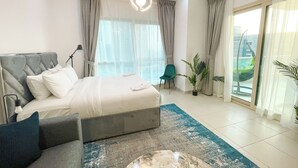 A modern hotel room with a large bed, a desk, and a view of the city.