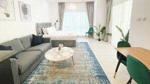 A modern hotel room with a bed, a sofa, a dining table, and a coffee table.