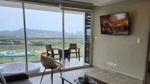 A modern living room with a large sliding glass door leading to a balcony, a sofa, a coffee table, and a TV mounted on the wall. - Relax and comfort| Apartment with private jacuzzi (La Boquilla)