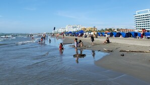 A beach with tents and a large building in the background. - Relax and comfort| Apartment with private jacuzzi (La Boquilla)