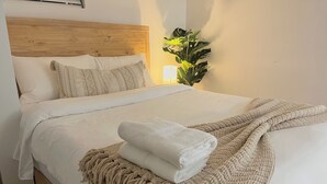 A neatly made bed with a wooden headboard, a beige throw blanket, and a white towel. - Chic Basement Suite ATL - Private Entrance & Free Charge and Park (Atlanta)