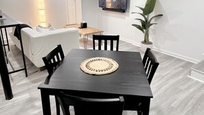 A modern living room with a dining area, a flat-screen TV mounted on the wall, and a potted plant. - Chic Basement Suite ATL - Private Entrance & Free Charge and Park (Atlanta)